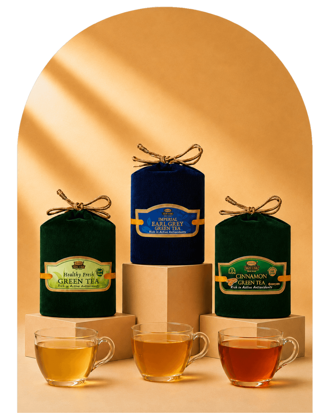 Three metal tea tins with gold lids are displayed on beige pedestals, with four clear glass teacups in front showing different tea colors. The tins are labeled Rooiberg Volcano, Chamaude Green Tea, and Earl Grey green tea.