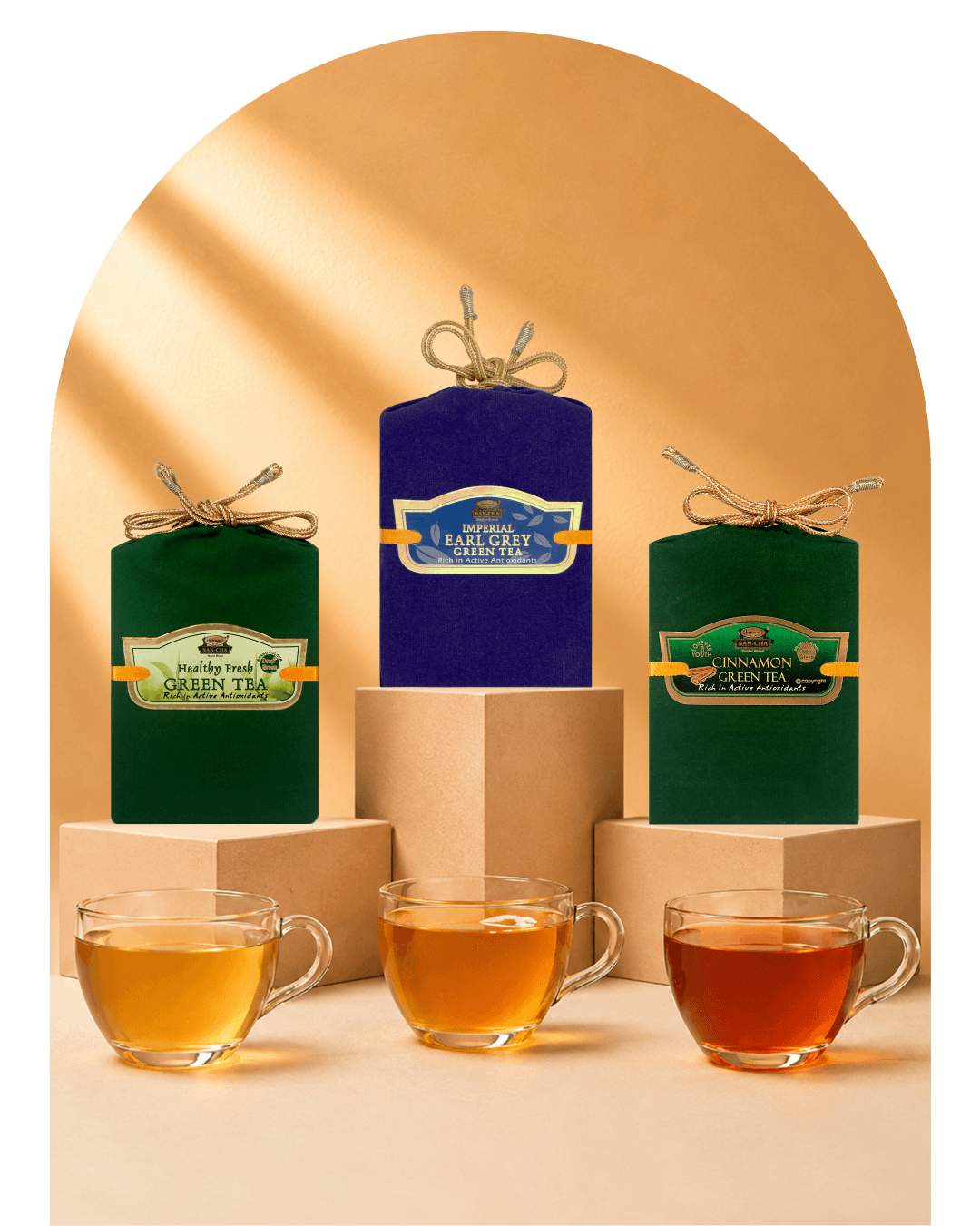Three metal tea tins with gold lids are displayed on beige pedestals, with four clear glass teacups in front showing different tea colors. The tins are labeled Rooiberg Volcano, Chamaude Green Tea, and Earl Grey green tea.