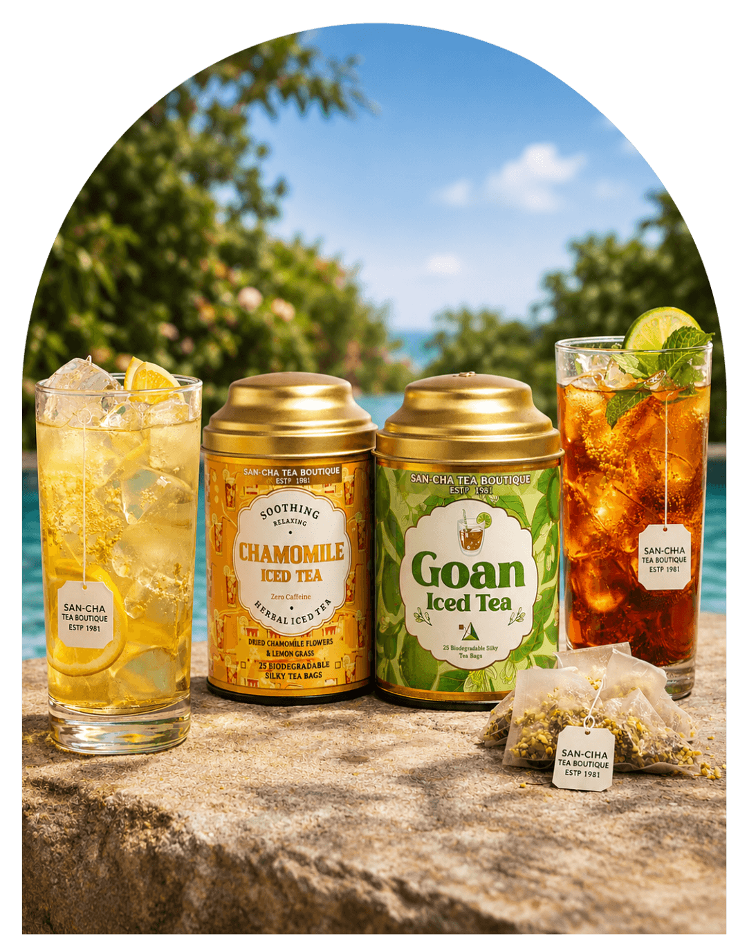 Two tea products displayed outdoors on a stone surface with two glasses of iced tea and a tea bag in front. The products are a gold canister of Chamomile Fold Tea and a green tin canister of Goan Iced Tea, with tropical beach scenery in the background.