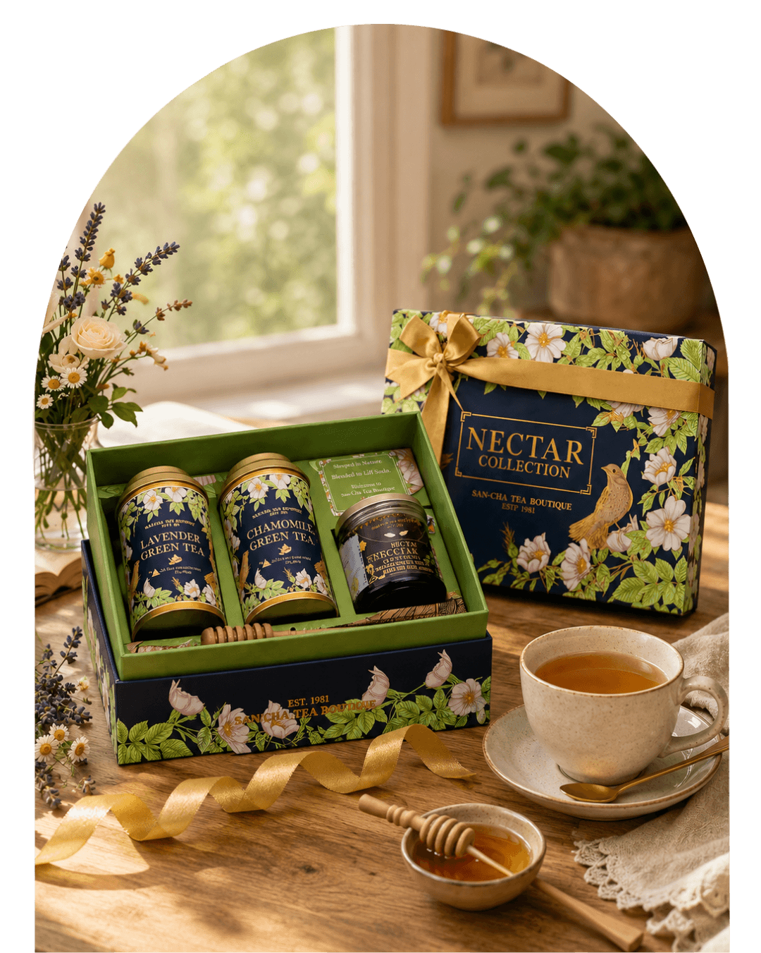 A tea gift set displayed on a wooden table by a window, featuring a floral-patterned box labeled 'NECTAR COLLECTION' with three tea tins and a small jar, alongside a cup of tea, honey dipper, and ribbon on a tabletop.