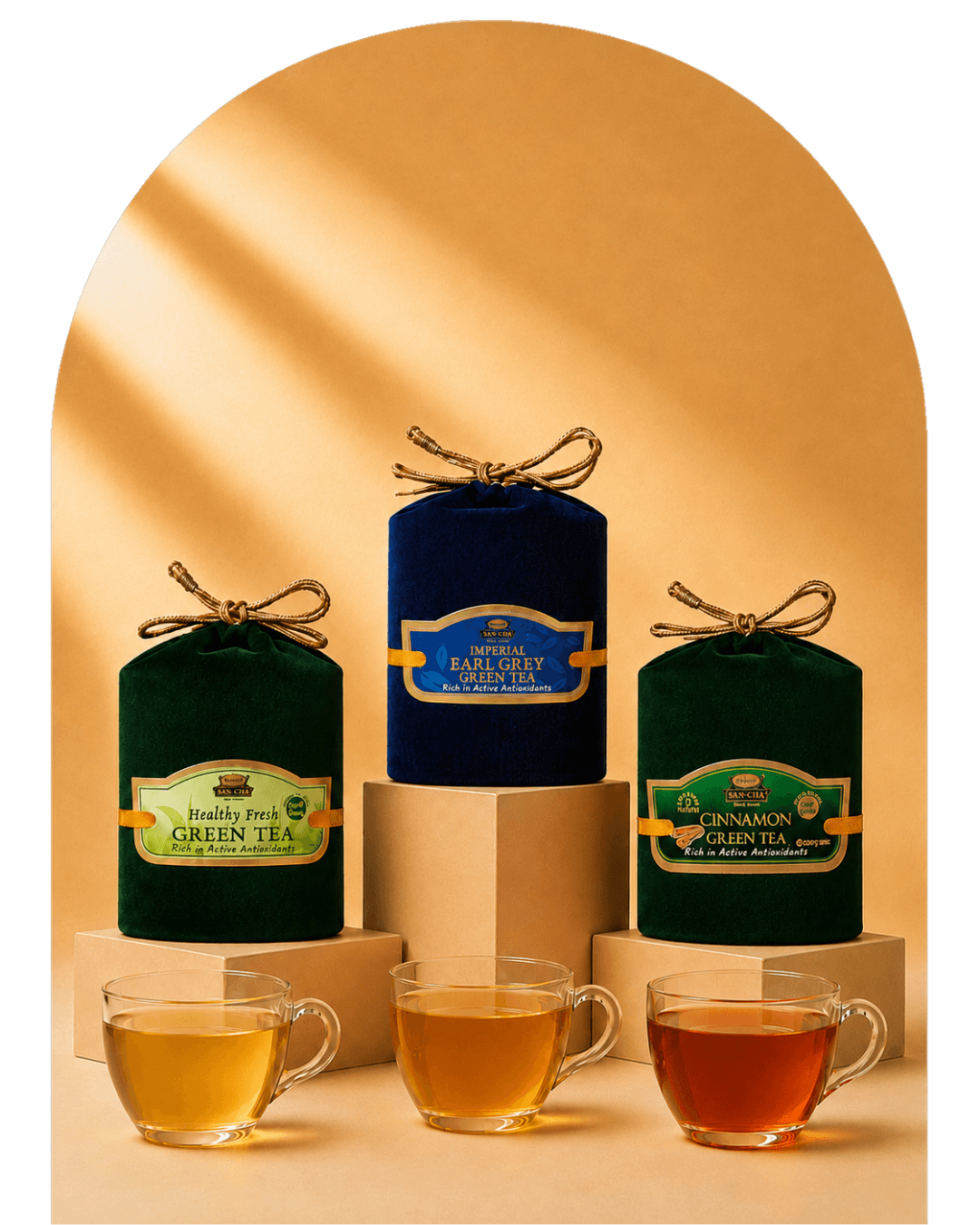 Three metal tea tins with gold lids are displayed on beige pedestals, with four clear glass teacups in front showing different tea colors. The tins are labeled Rooiberg Volcano, Chamaude Green Tea, and Earl Grey green tea.