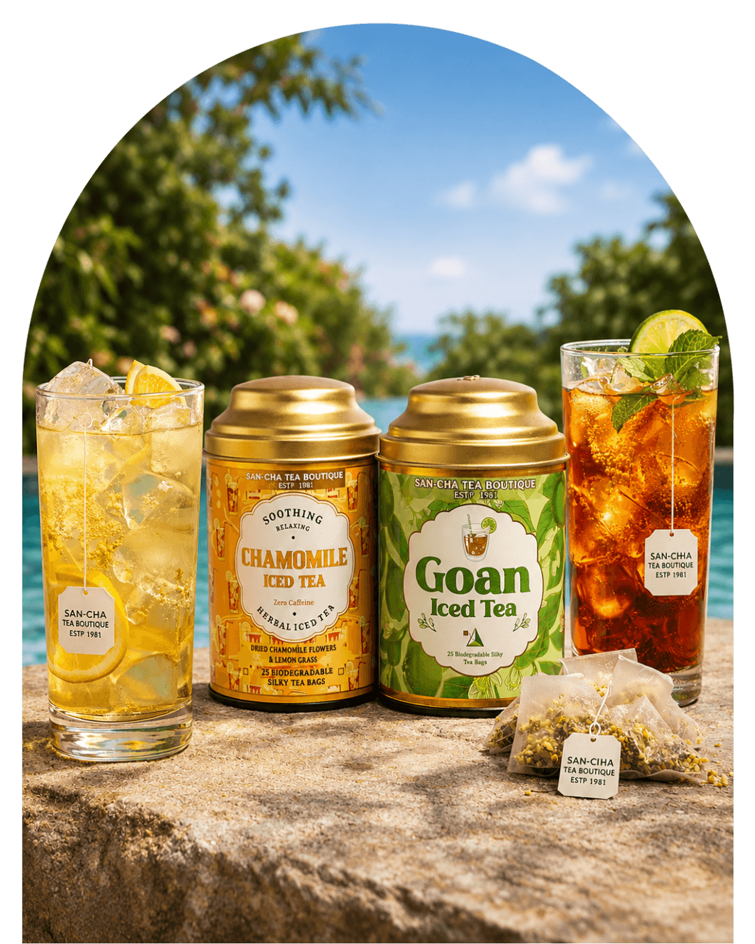 Two tea products displayed outdoors on a stone surface with two glasses of iced tea and a tea bag in front. The products are a gold canister of Chamomile Fold Tea and a green tin canister of Goan Iced Tea, with tropical beach scenery in the background.