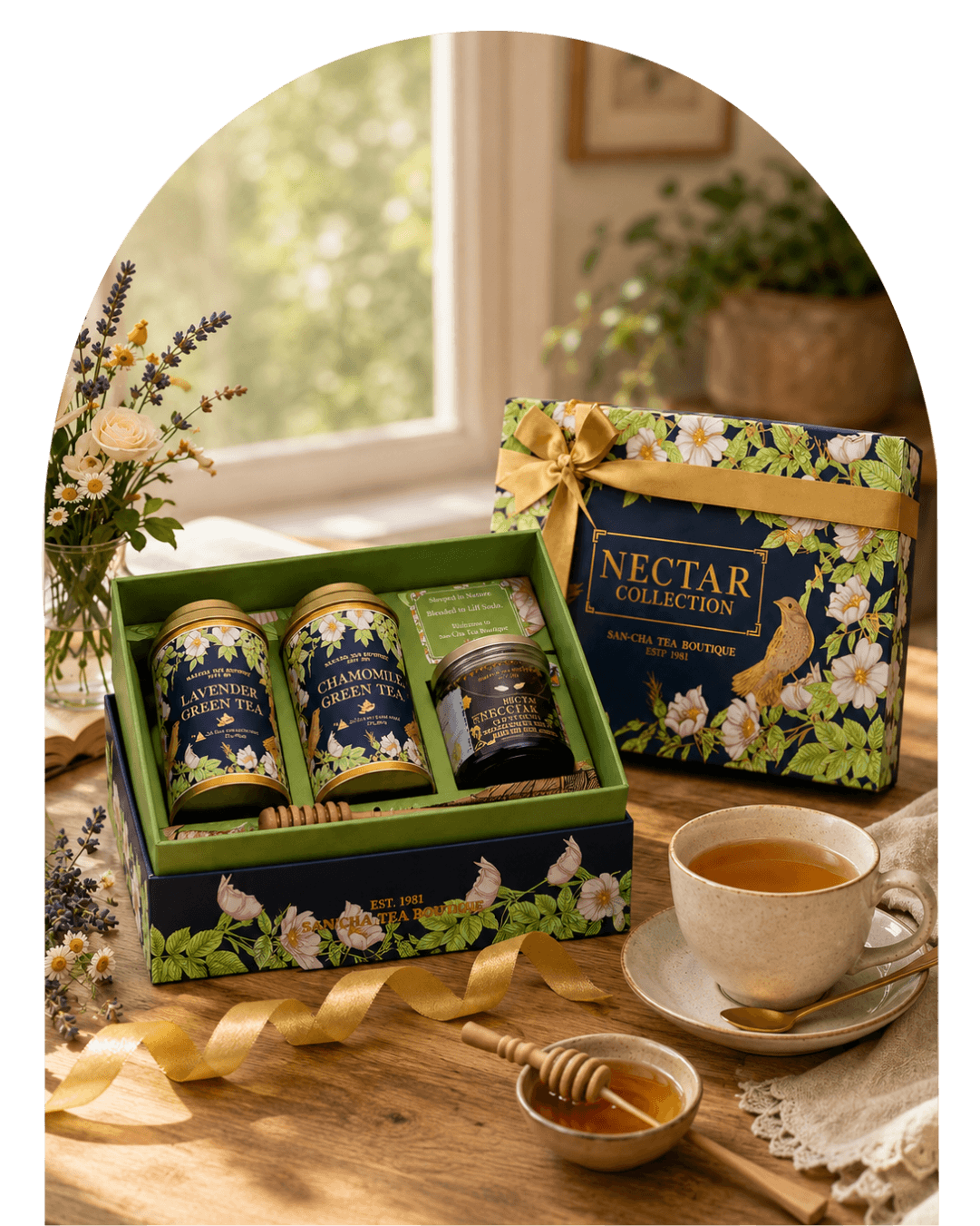 A tea gift set displayed on a wooden table by a window, featuring a floral-patterned box labeled 'NECTAR COLLECTION' with three tea tins and a small jar, alongside a cup of tea, honey dipper, and ribbon on a tabletop.